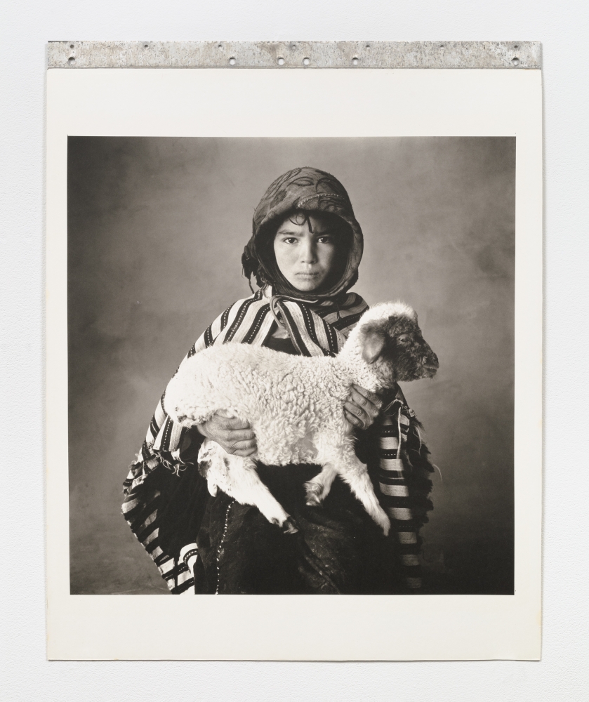 Black and white photographic portrait of a child holding a lamb.