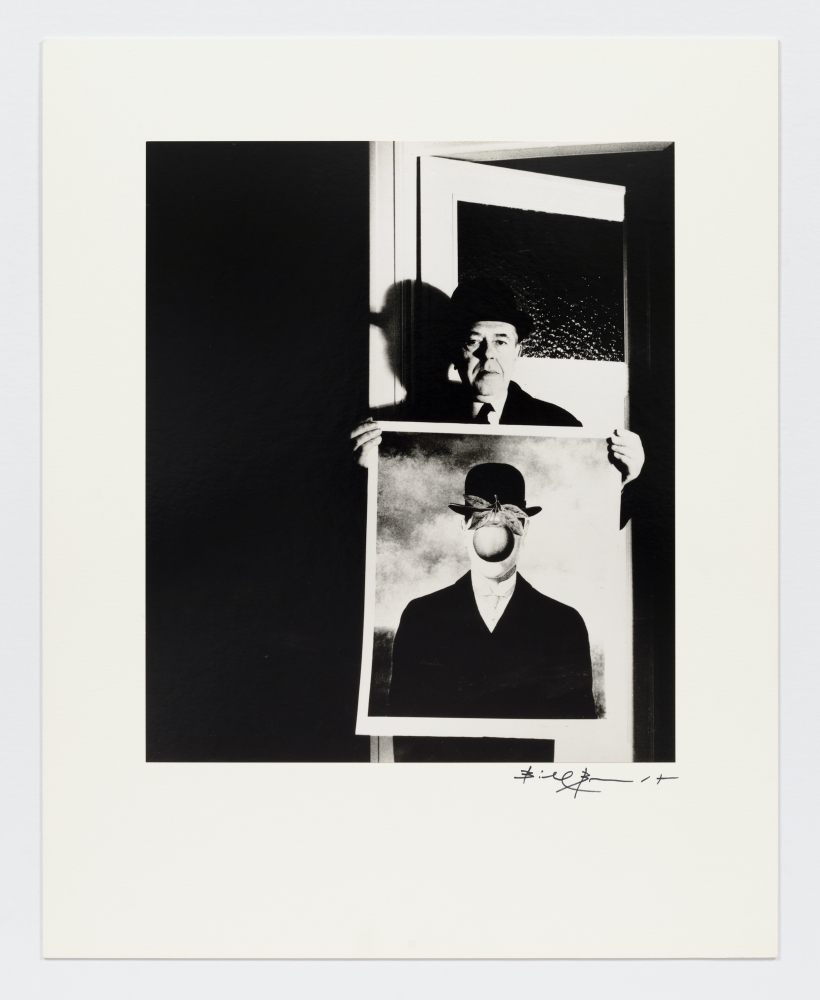 Black and white photographic portrait of man holding Magritte's "The Son of Man" by Bill Brandt.