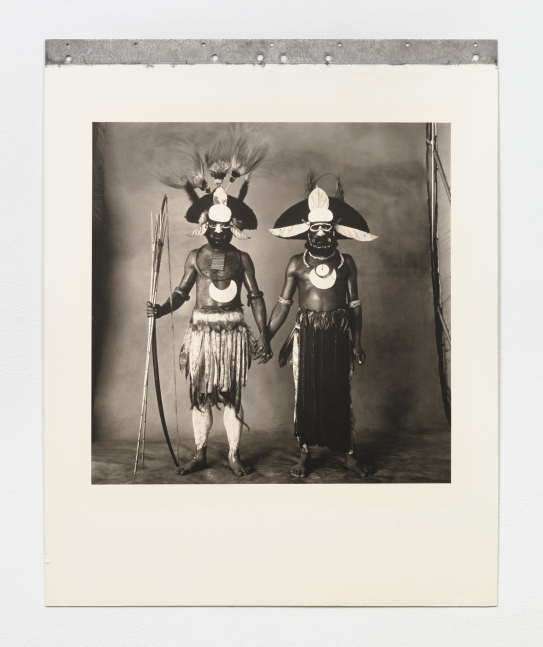 Black and white double portrait of two New Guinea warriors holding hands.
