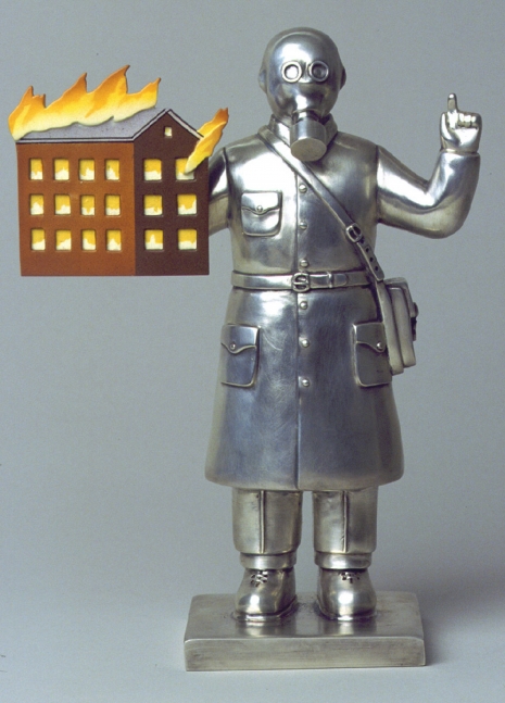 Stainless steel statue of a character with a gas mask and a model of a burning house.