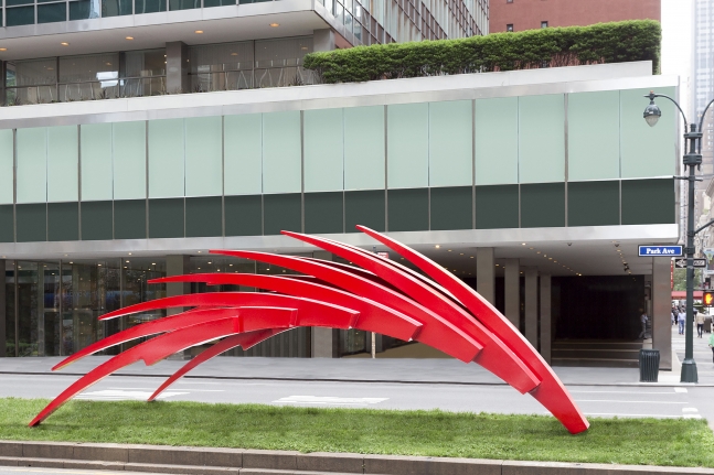 An installation shot of Santiago Calatrava's sharp, red, and angular stainless steel sculpture sits atop grass on Park Avenue.