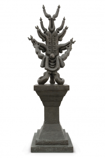 Bronze sculpture with praying figurine atop pedestal.